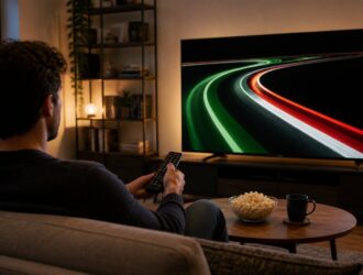 Viewer watching green, white and red race-track light trails on television.