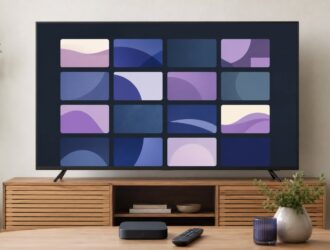 A home television displaying a neutral grid of abstract streaming tiles with a compact streaming device and remote.